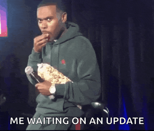 a man in a green hoodie is eating popcorn and holding a microphone .