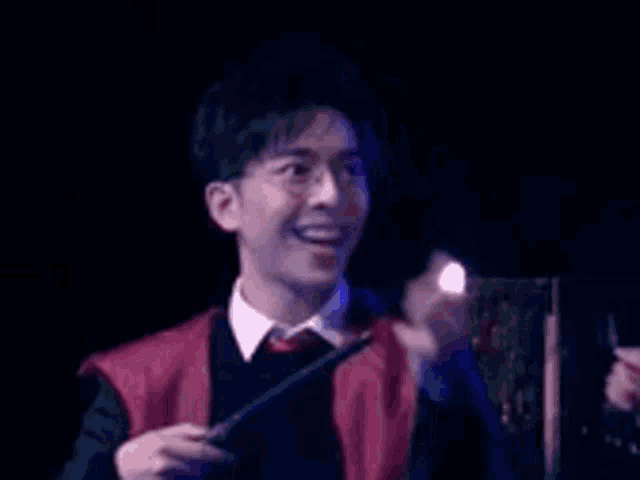 a man in a harry potter costume is holding a wand and giving a thumbs up .