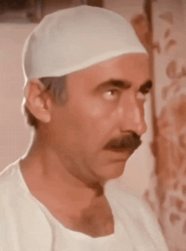 a man wearing a white hat and a white shirt has a mustache