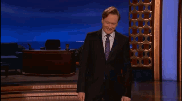 a man in a suit and tie is standing in front of a desk
