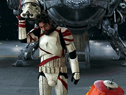 a man in a storm trooper costume holds his helmet over his head
