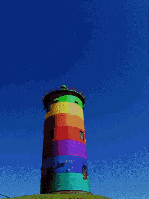 a rainbow colored lighthouse against a yellow sky