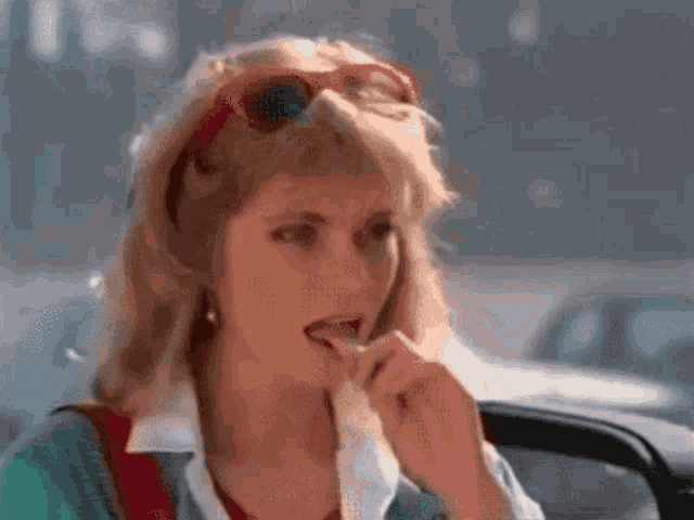 a woman is sitting in a car with her eyes closed and smoking a cigarette .