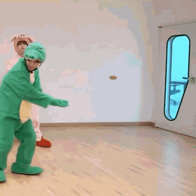 a man in a pig costume is standing next to a man in a green frog costume .