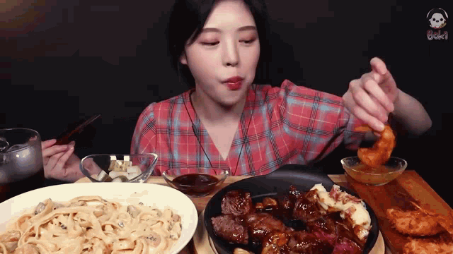 a woman in a plaid shirt is sitting at a table eating a variety of food