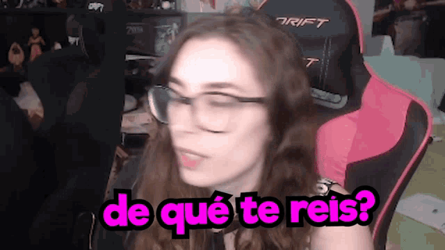 a woman wearing glasses is sitting in a pink gaming chair and says de que te reis ?