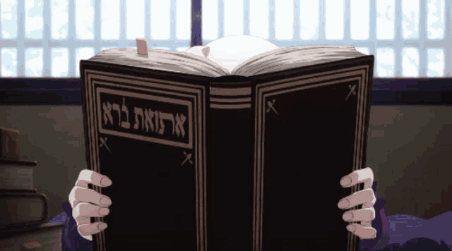a person is holding a book with hebrew writing on it