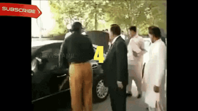 a group of men are standing around a car with the number 4 on the hood