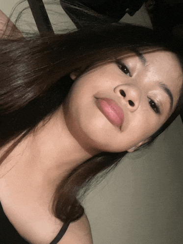 a close up of a girl 's face with a black tank top on