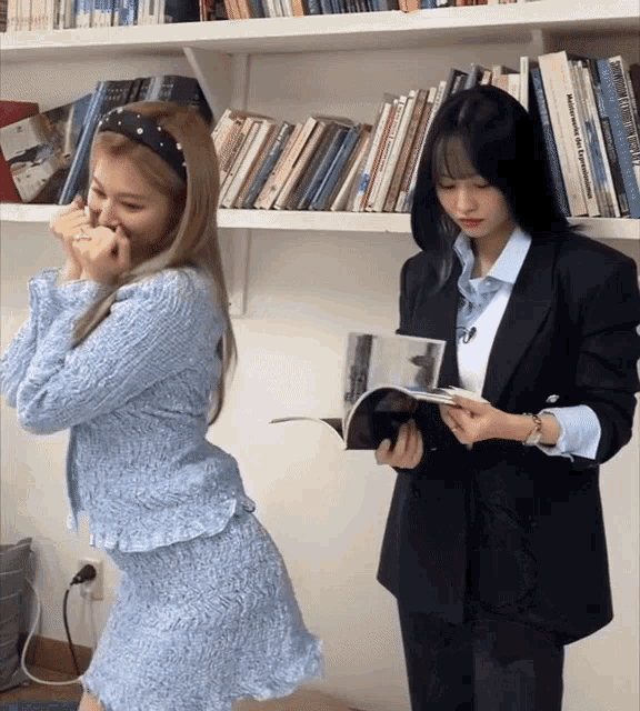 two women are standing in front of a bookshelf and one is holding a book that says mathematics and statistics