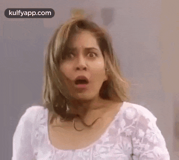 a woman with a surprised look on her face is wearing a white top .