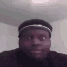 a man wearing a hat and a headband is smiling .