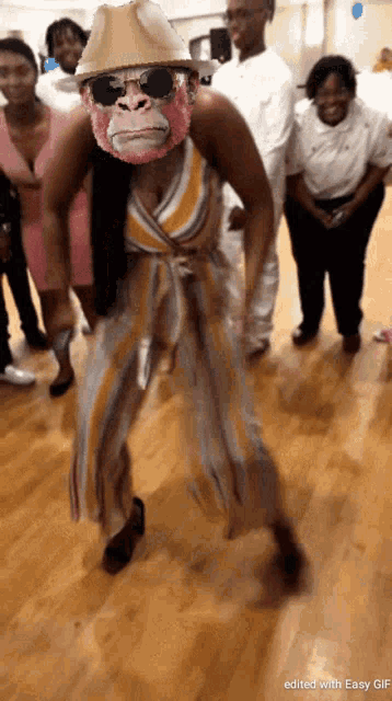 a woman wearing a monkey mask and sunglasses is dancing in front of a group of people