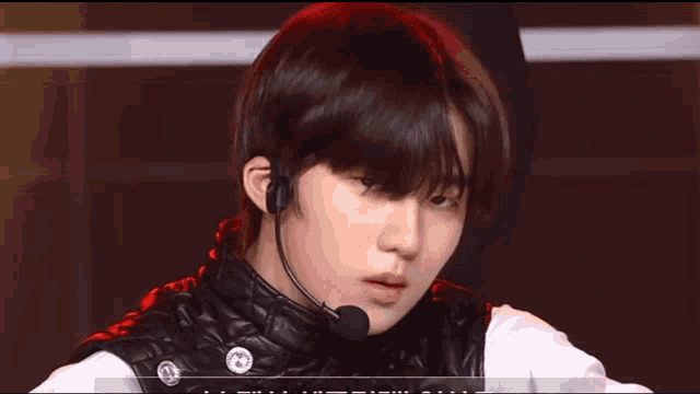 a young man wearing a black vest and a microphone