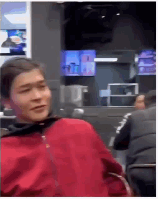 a man in a red jacket sits in a restaurant
