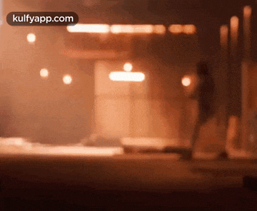 a blurry picture of a person standing in front of a building holding a torch .