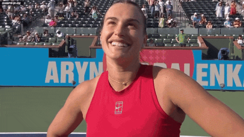 a woman in a red tank top is smiling in front of a banner that says " aryn "