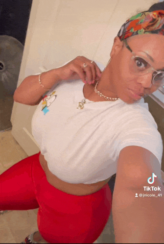a woman wearing glasses and a headband is taking a selfie on tik tok