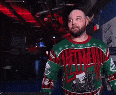 a man wearing an ugly christmas sweater that says slayer