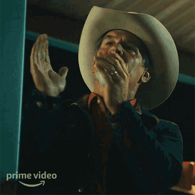a man in a cowboy hat is applauding in front of a prime video logo
