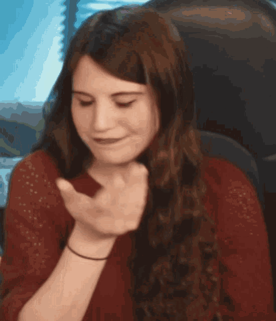 a woman in a red shirt is sitting in a chair with her hand on her face