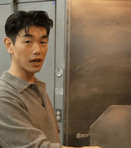a man in a grey shirt stands in front of a stainless steel wall