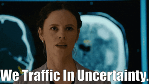 a woman in a lab coat stands in front of a screen that says " we traffic in uncertainty "