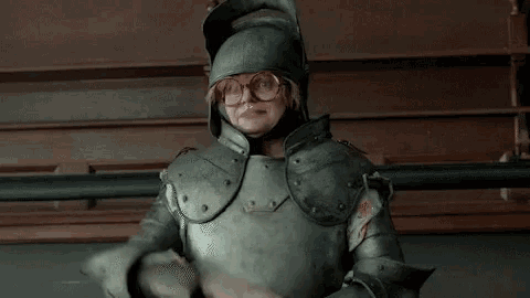a man in armor is standing in a room with the words `` like a steak hache '' written above him .
