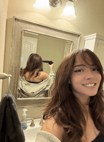 a woman is taking a selfie in front of a mirror while holding a gun