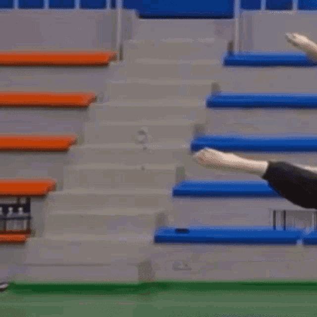 a person wearing a mask is walking down stairs in a stadium while another person throws a frisbee .