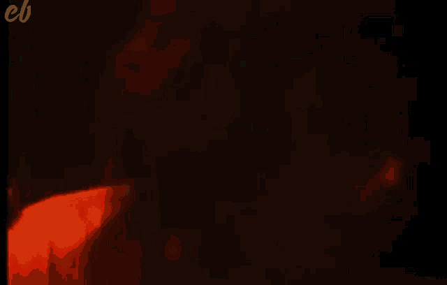 a man is singing into a microphone in a dark room with red lights behind him .