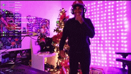 a man wearing headphones is standing in front of a christmas tree .