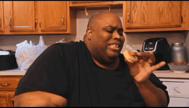 a man in a black shirt is eating a hamburger