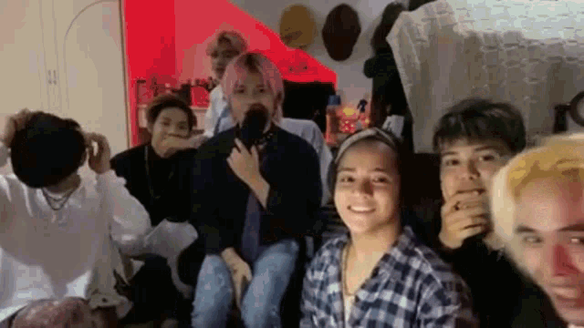 a group of people are sitting in a room with a red light in the background .
