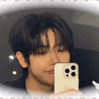 a young man is taking a picture of himself in the mirror with his cell phone .