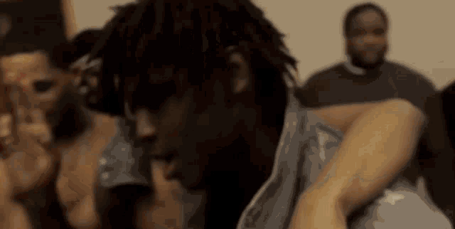 a man with dreadlocks is sitting in a room with a group of people .