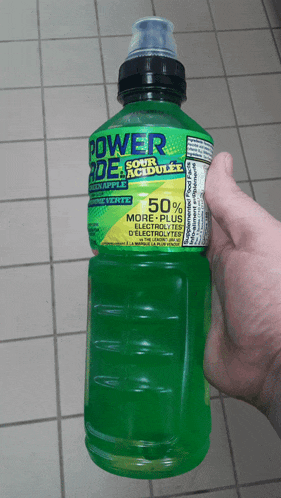 a hand is holding a bottle of powerade in sour acidulated