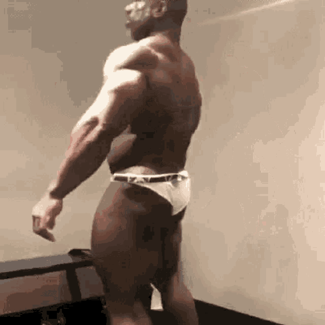 a man in a white underwear is standing in a locker room .