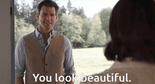 a man in a vest is talking to a woman who says " you look beautiful "