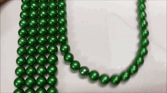 a string of green beads on a white surface .