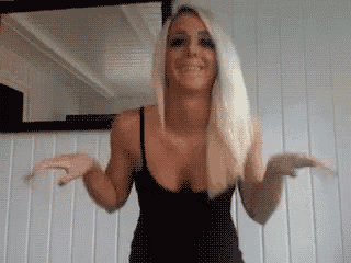 a woman in a black tank top is dancing in front of a mirror .