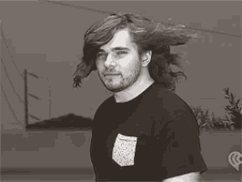 a man with long hair is wearing a black shirt with a pocket