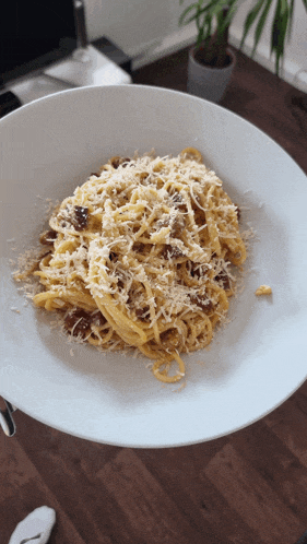 a white plate topped with pasta and cheese on a wooden table