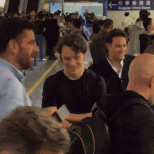 a group of people are gathered in front of a sign that says baggage check room