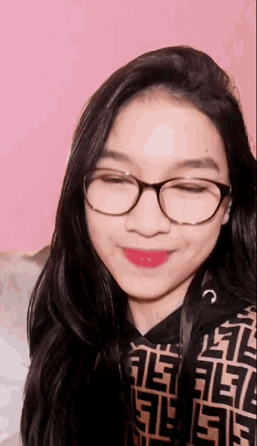 a young girl wearing glasses and a fendi shirt