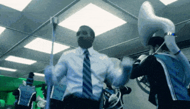 a man in a suit and tie is dancing with a man in a blue shirt that says ' miami ' on the side