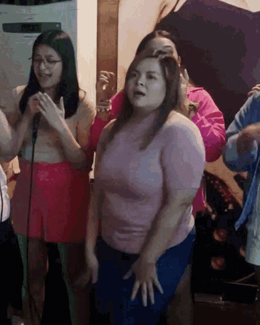 a group of women are singing and dancing in front of a microphone ..