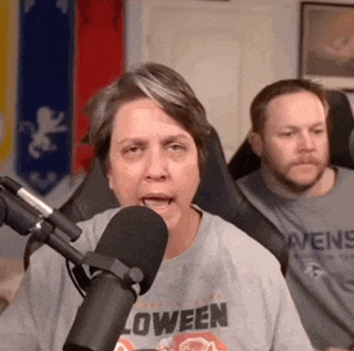 a woman wearing a loween t-shirt is talking into a microphone