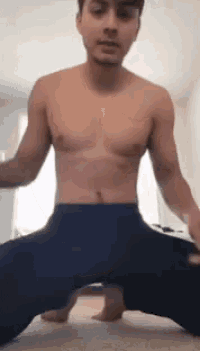 a shirtless man is kneeling down on the floor with his legs crossed