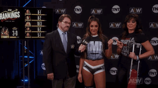 a man and two women standing in front of a wall that says aew on it